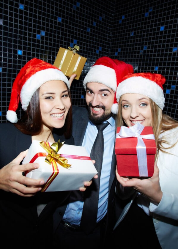 3 people holding presents and wearing christmas hats