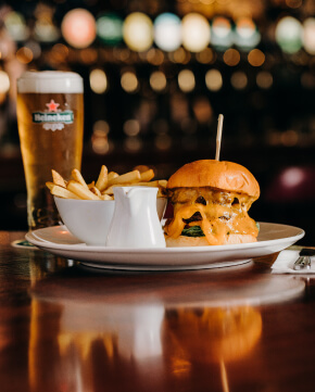 image of burger and chips with a pint of heineken