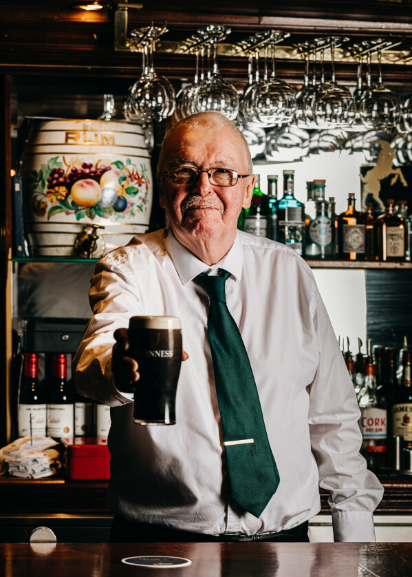 Man holding a pint of guinness behind the bar